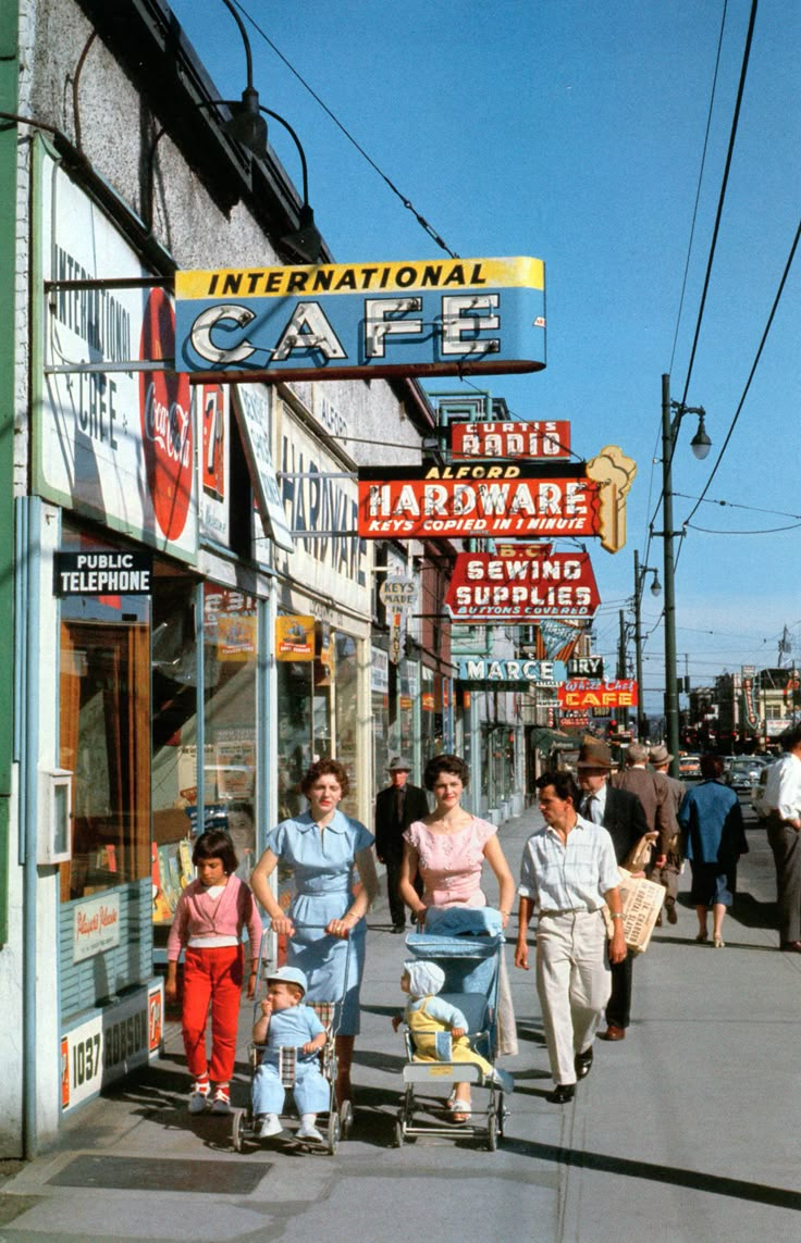 people are walking down the street in front of shops