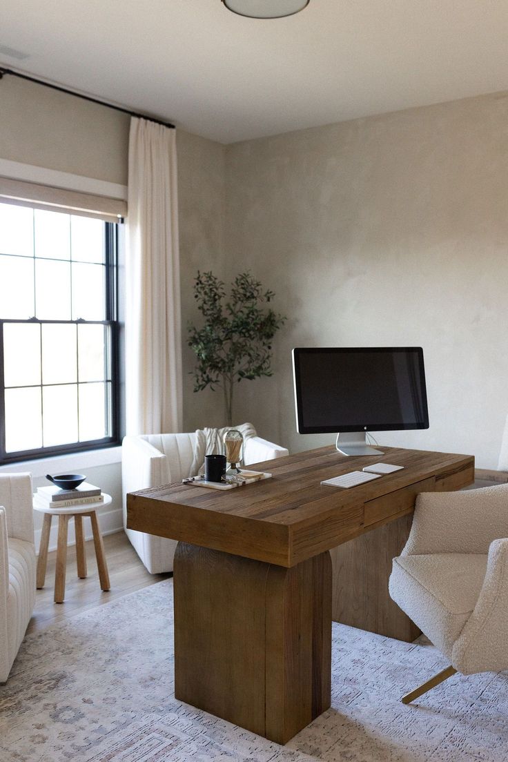 a living room with a desk, chair and computer monitor on top of the table