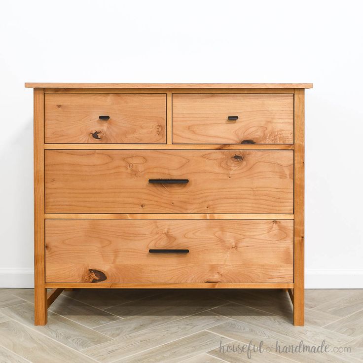 a wooden dresser sitting on top of a hard wood floor next to a white wall