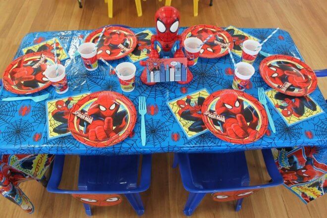 a spiderman themed table set up with plates, cups and napkins on it