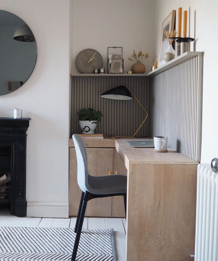 a living room with a fireplace, mirror and desk in the corner next to it