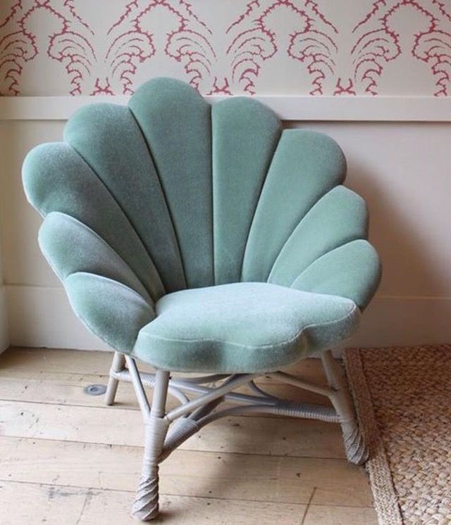 a blue shell chair sitting on top of a wooden floor next to a white wall