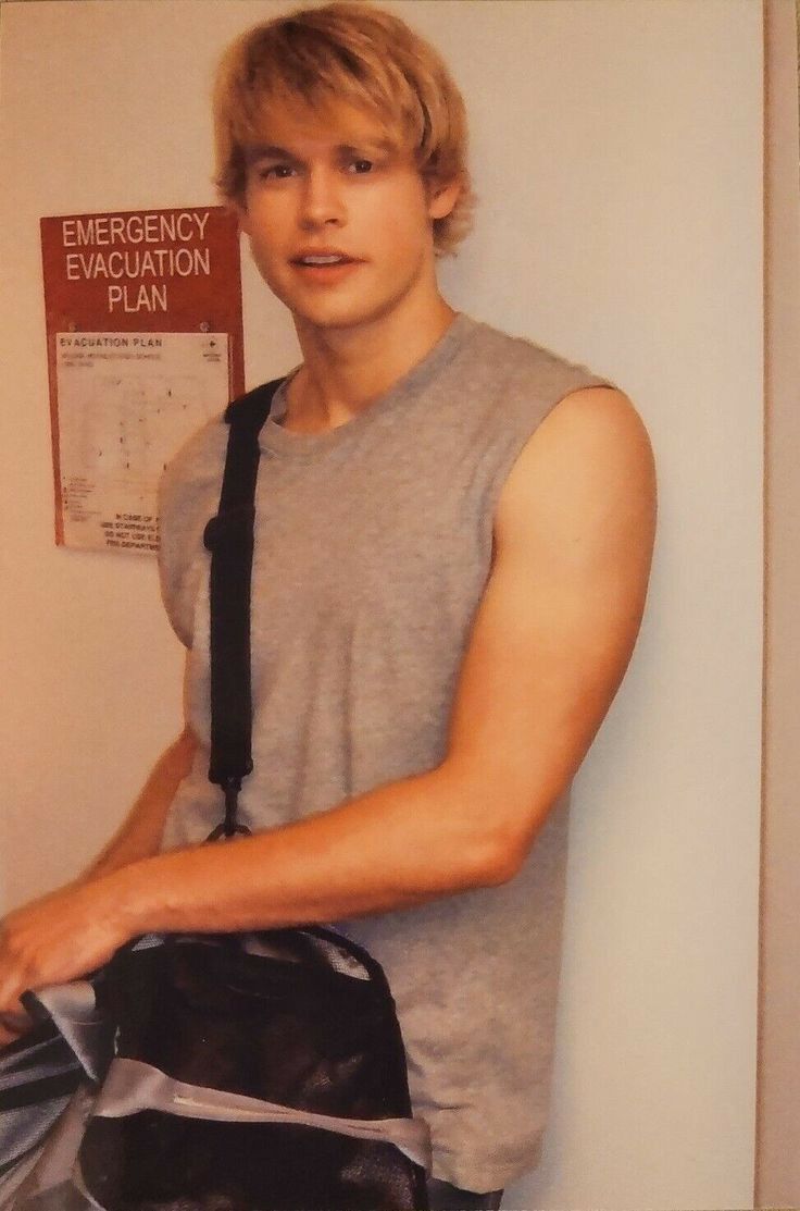 a young man standing next to a wall with an emergency education sign on it's side