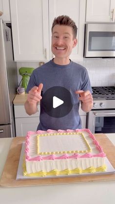 a man standing in front of a cake on top of a counter next to a stove