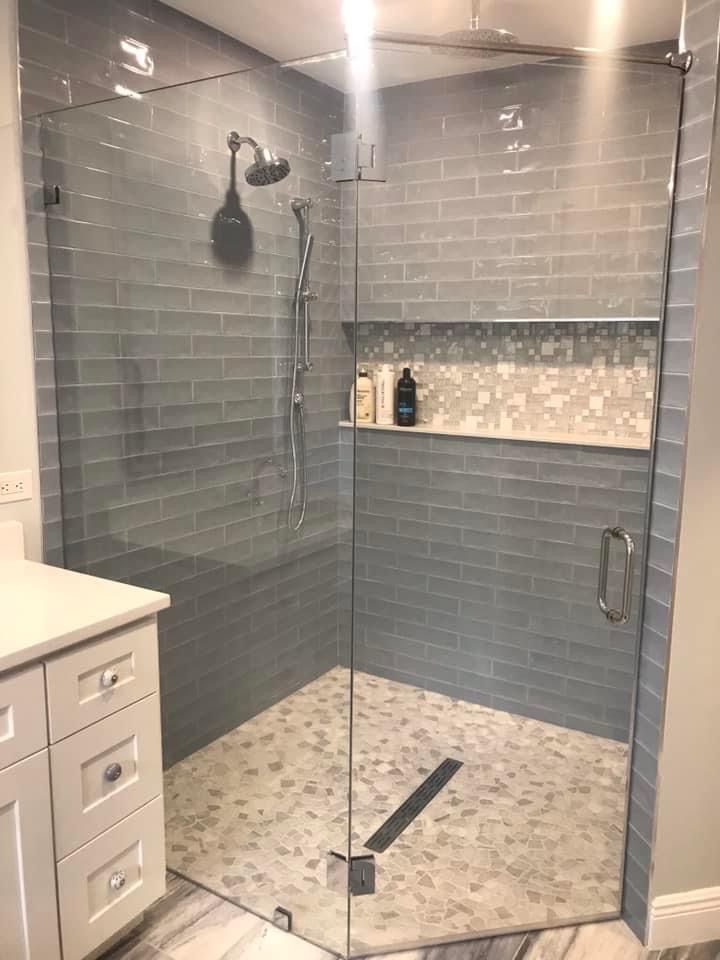 a walk in shower sitting next to a white sink and counter top under a faucet