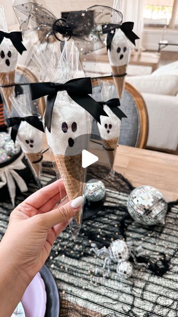 a person holding an ice cream cone decorated with skulls and ghost faces on it's head