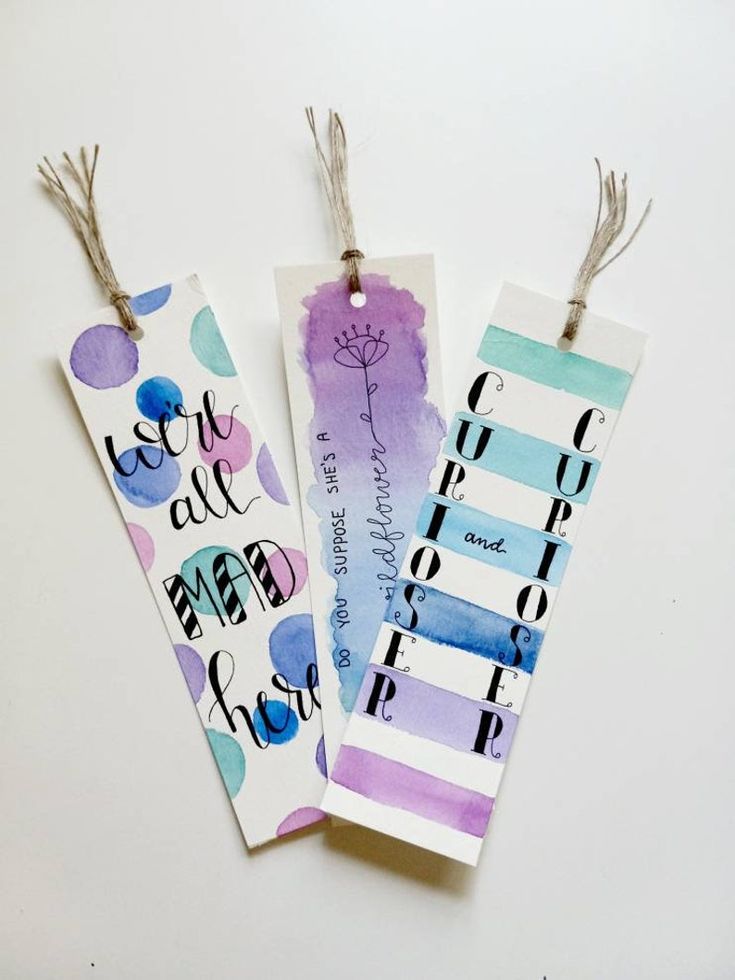 three bookmarks with writing on them are hanging from twine strings and decorated with colored paper