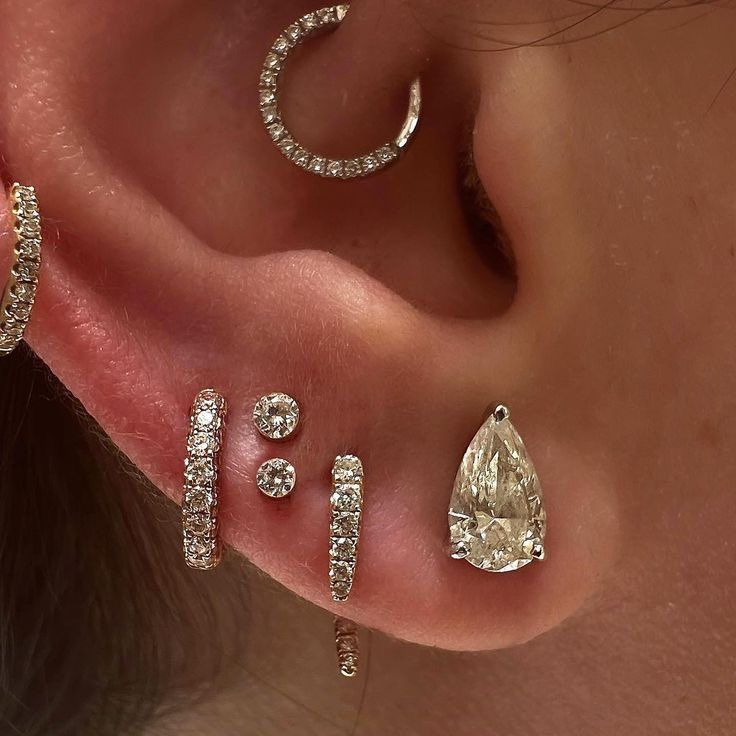 a woman with three different ear piercings on her left ear and one is wearing a diamond ring