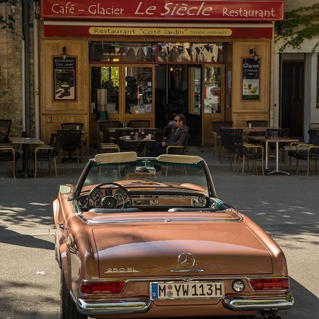 an old car parked in front of a cafe