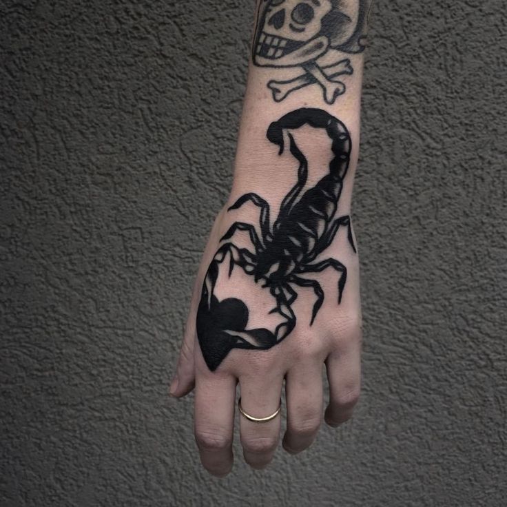 a person's hand with a scorpion tattoo on it