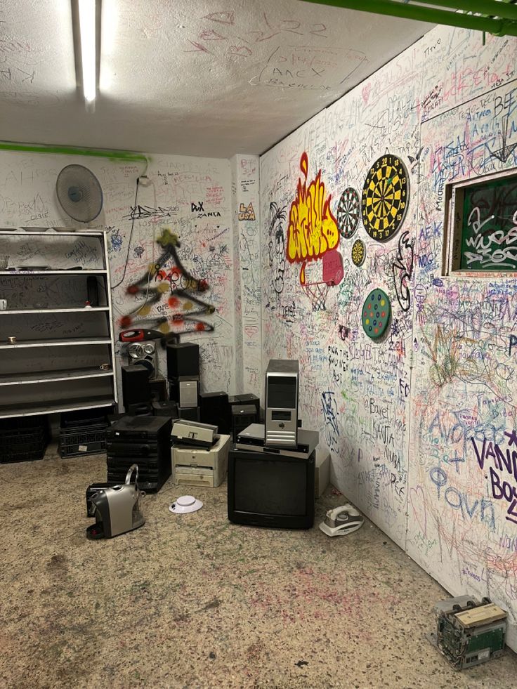 a room with graffiti all over the walls and various electronic equipment on the floor in front of it