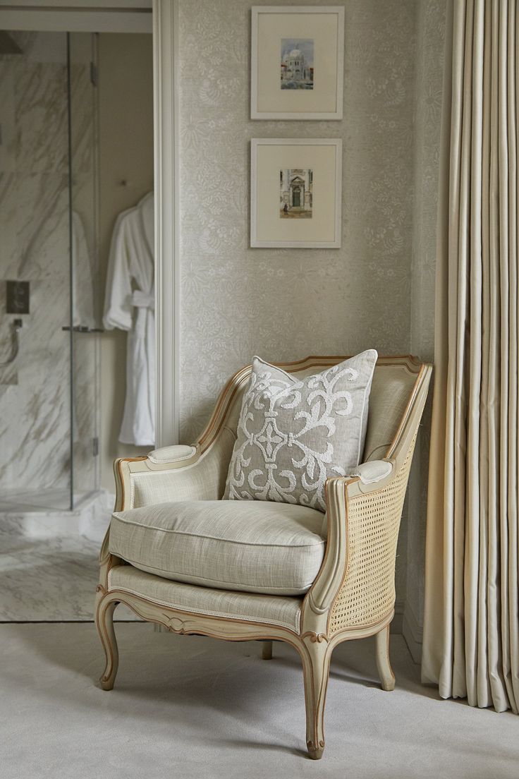 a white chair sitting in front of a shower next to a wall with pictures on it