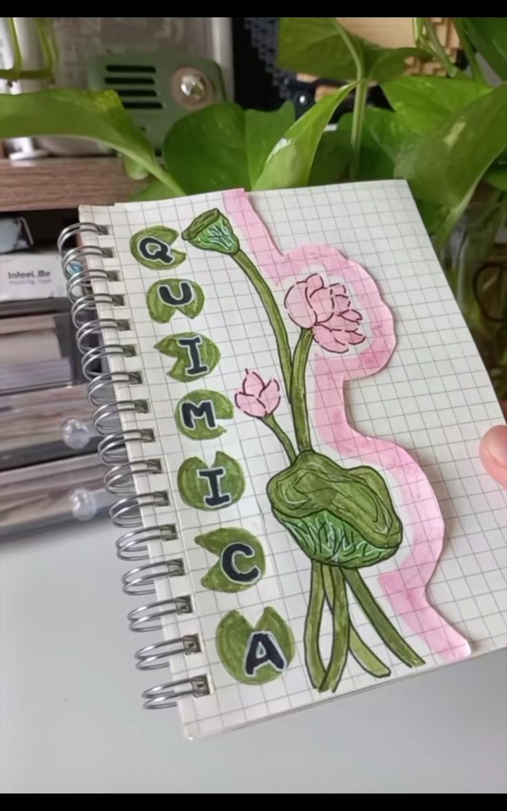 someone is holding up a spiral notebook with an image of a frog and flowers on it