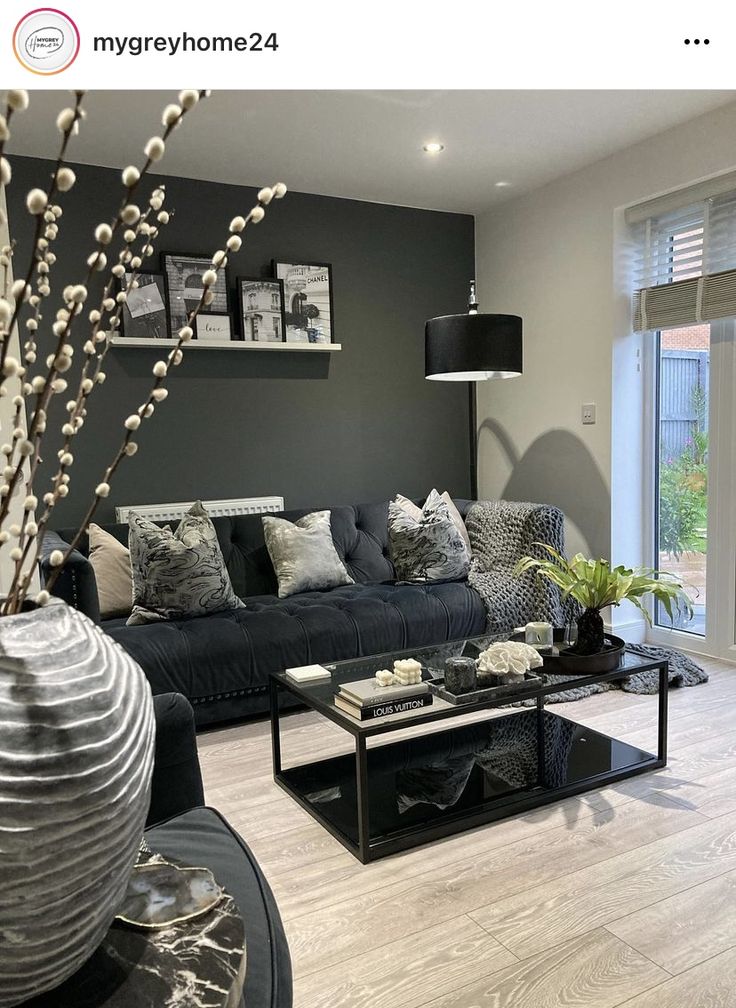 a living room filled with black furniture and lots of pillows on top of it's couches