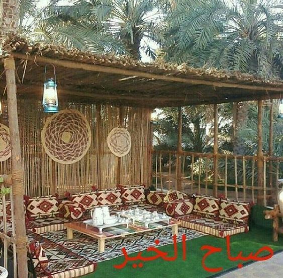 an outdoor living area with couches, tables and rugs on the grass in front of palm trees