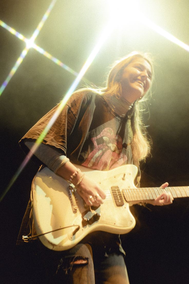 a woman with long hair playing an electric guitar