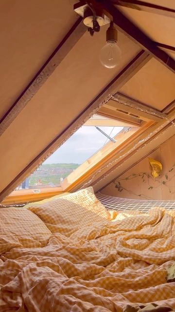 the bed is made and has yellow sheets on it, with an open window in the background