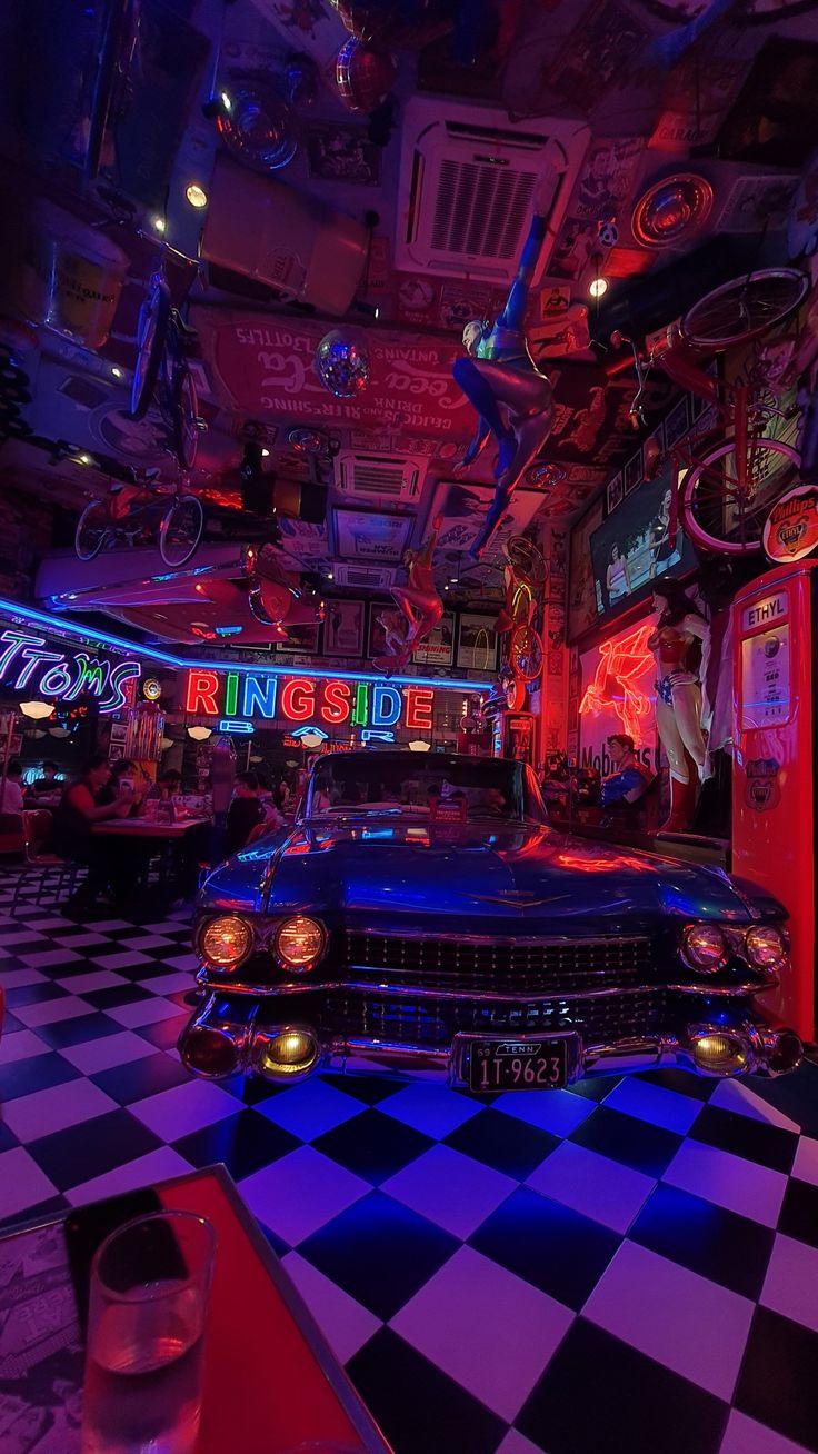 a car is parked in the middle of a checkered floor with neon lights on it