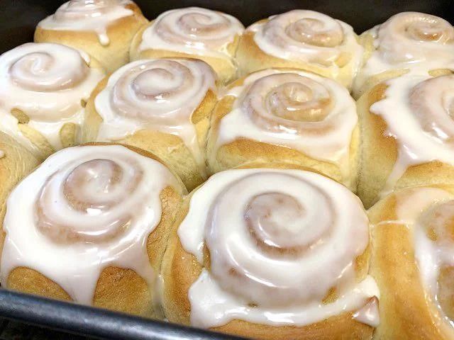 a baking pan filled with cinnamon rolls covered in icing