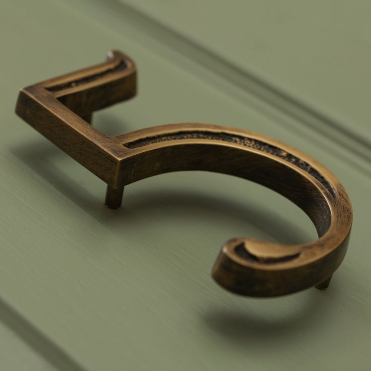 a close up of a wooden handle on a green cabinet with wood grained finish