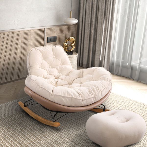 a rocking chair and ottoman in a living room with beige walls, rugs and curtains