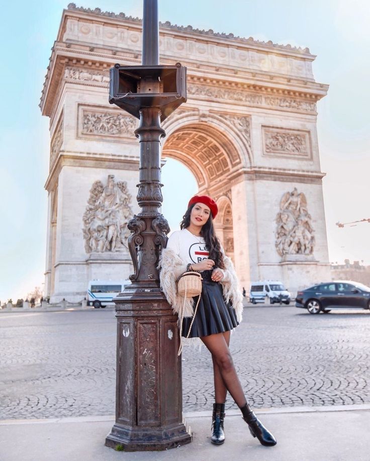 a woman standing next to a lamp post in front of the arc de trio triumph