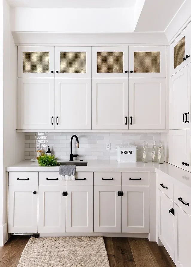 a kitchen with white cabinets and wooden floors