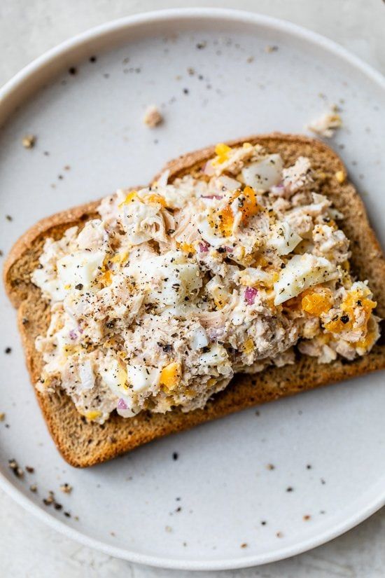 a white plate topped with a piece of bread covered in chicken salad