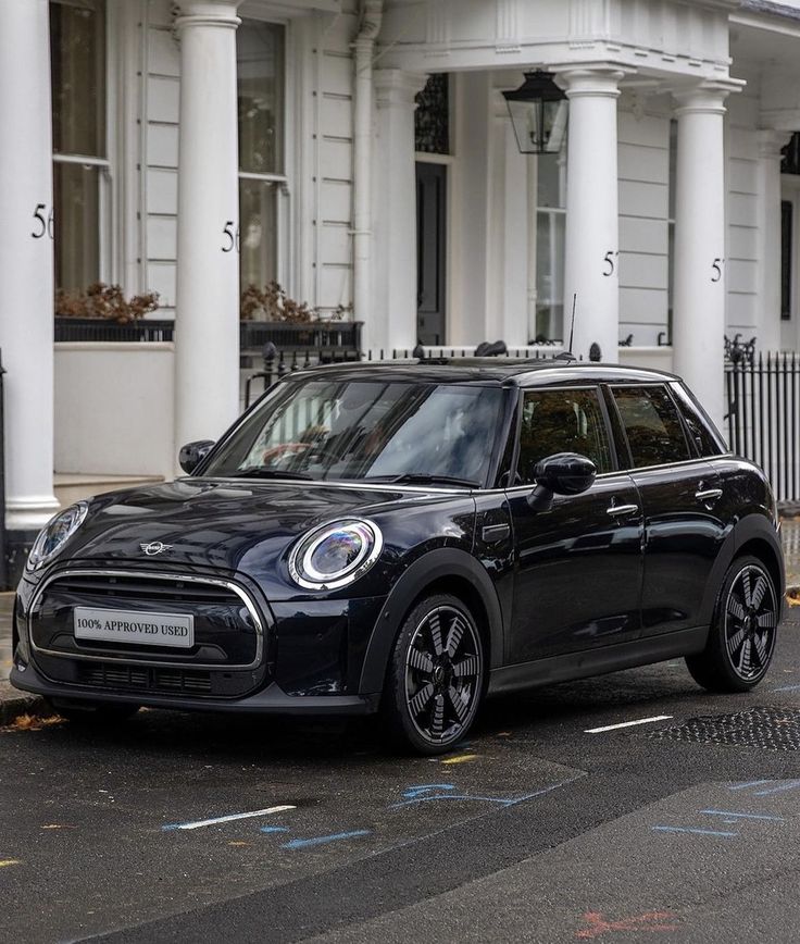 a small black car parked in front of a white building