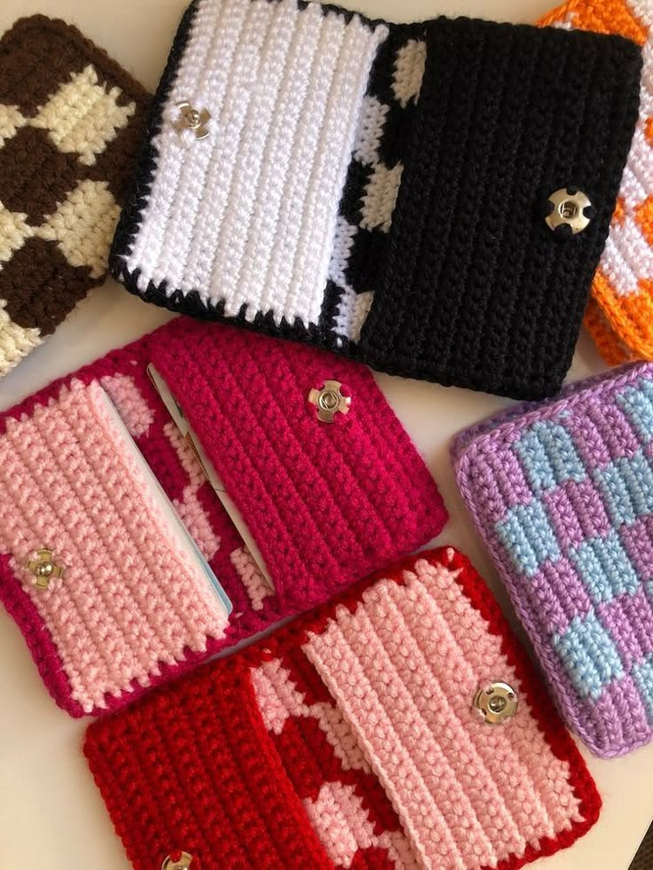 four crocheted purses sitting on top of a white table next to each other