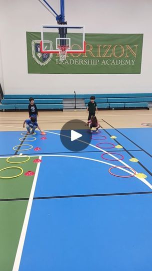 kids playing basketball on an indoor court with blue and green flooring in the background