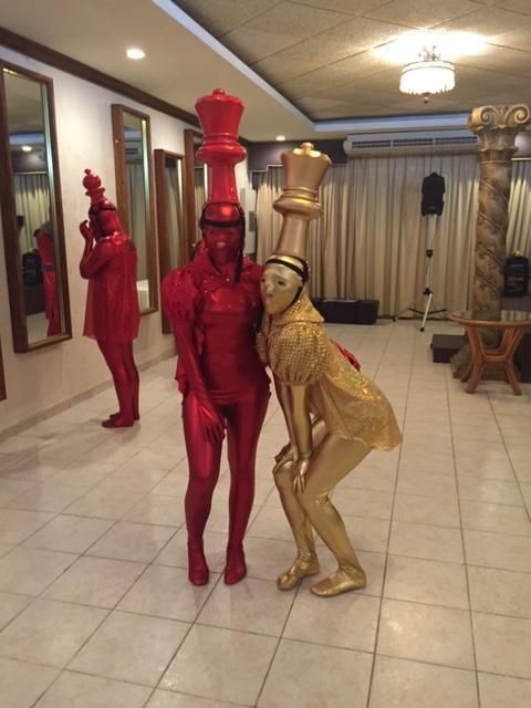 two people dressed in red and gold are standing next to each other, one is holding a lamp