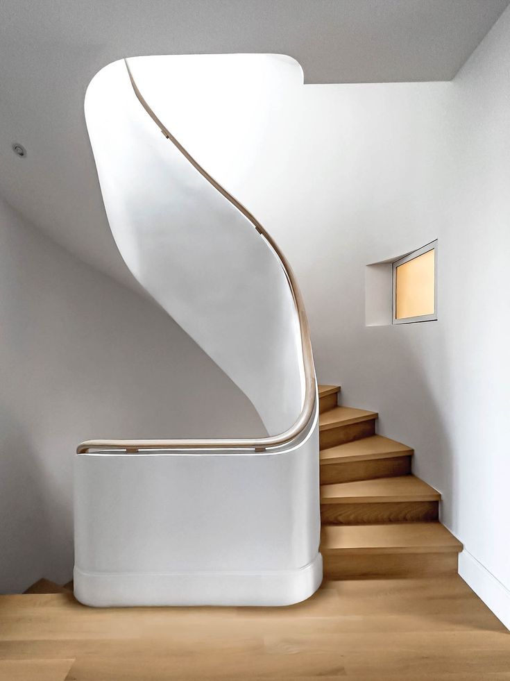 there is a white spiral staircase in the house with wood flooring and handrails