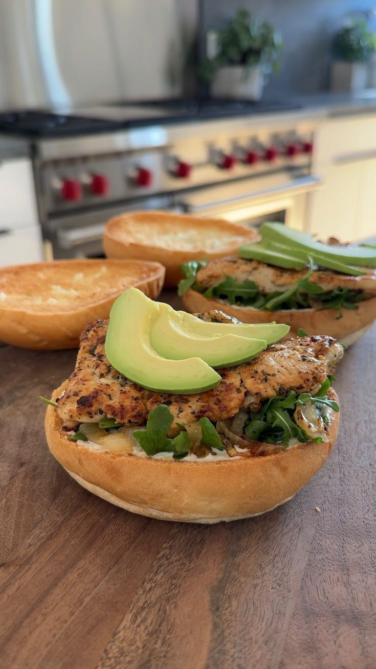 sandwiches with avocado and spinach sitting on a table in front of an oven