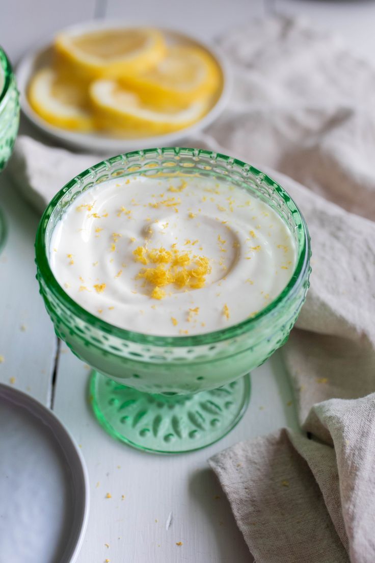 two glasses filled with yogurt and lemons on top of a white table