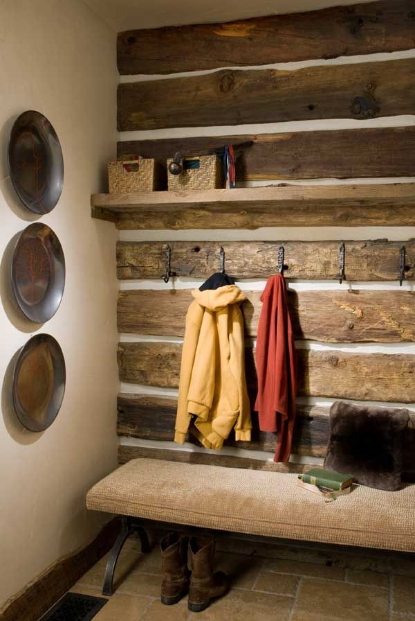 a wooden bench sitting in front of a wall mounted coat rack