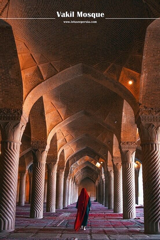 a person in a red robe is walking through an ornate building with columns and arches