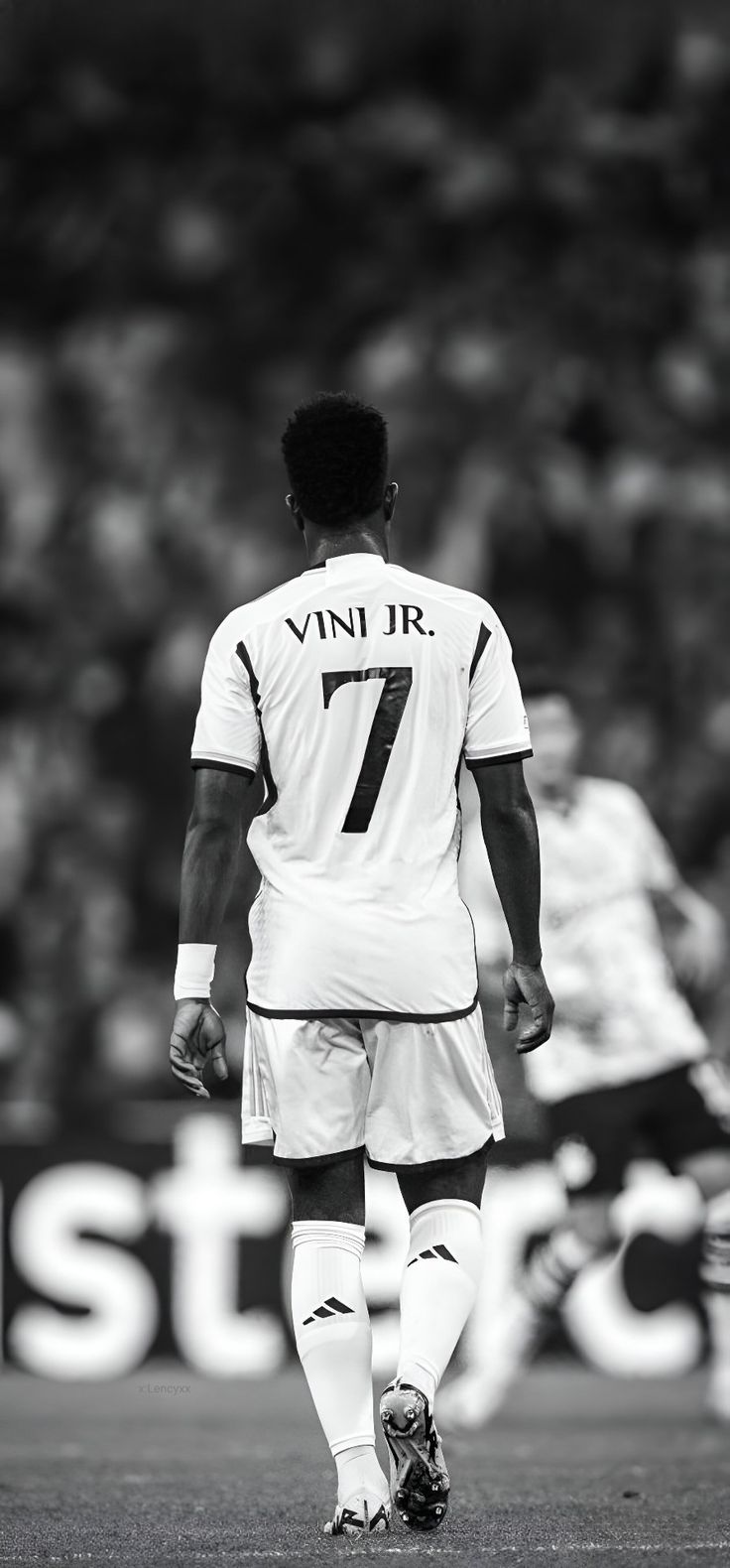 a black and white photo of a soccer player on the field with his back to the camera