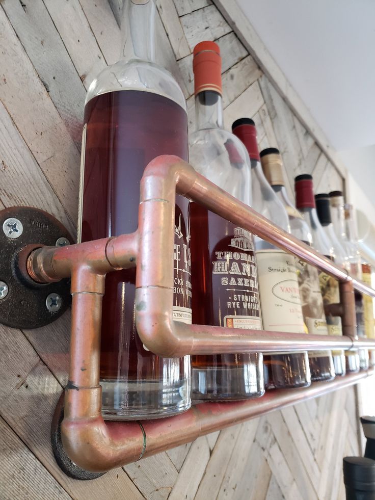 a metal pipe shelf with bottles on it and a bottle holder attached to the wall