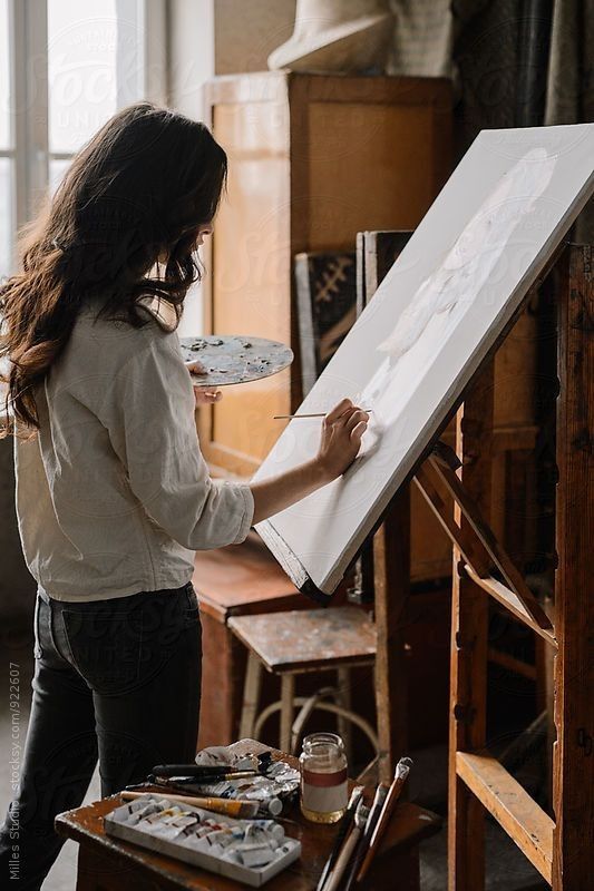 a woman standing in front of an easel painting