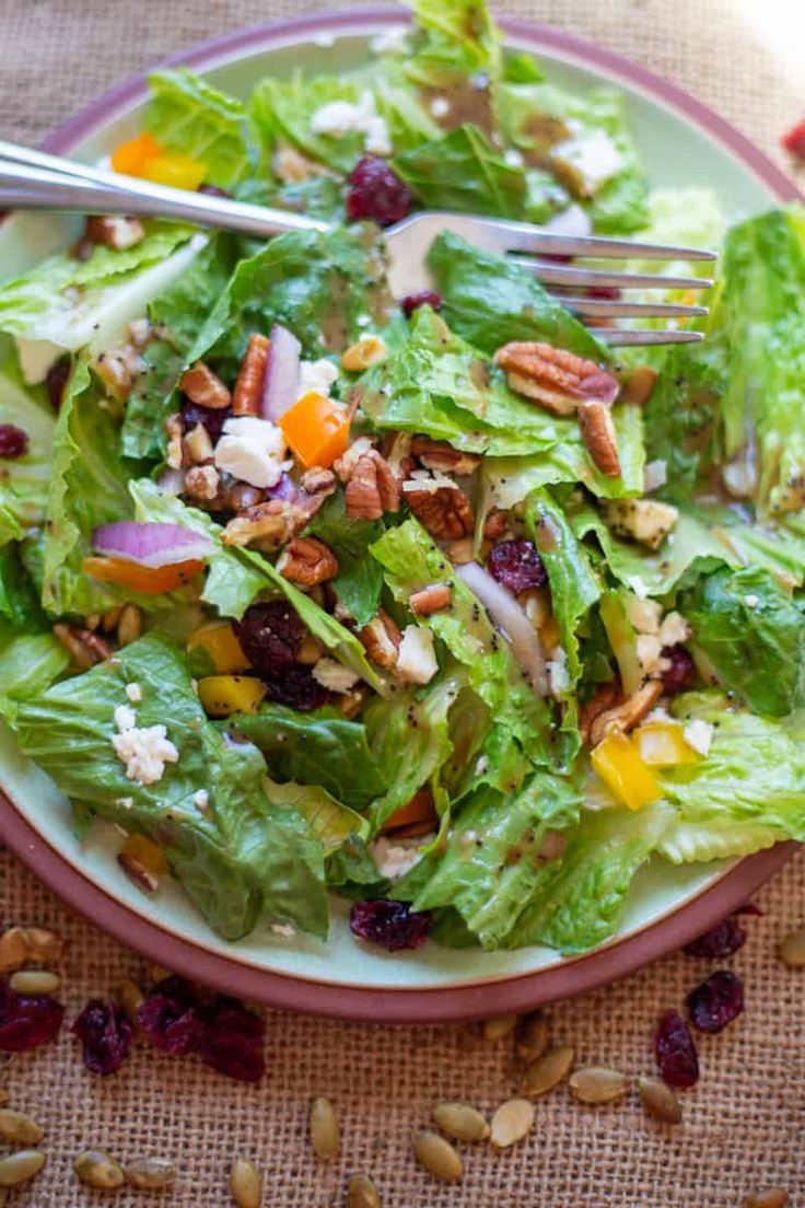 a salad with lettuce, cranberries and pecans on a plate