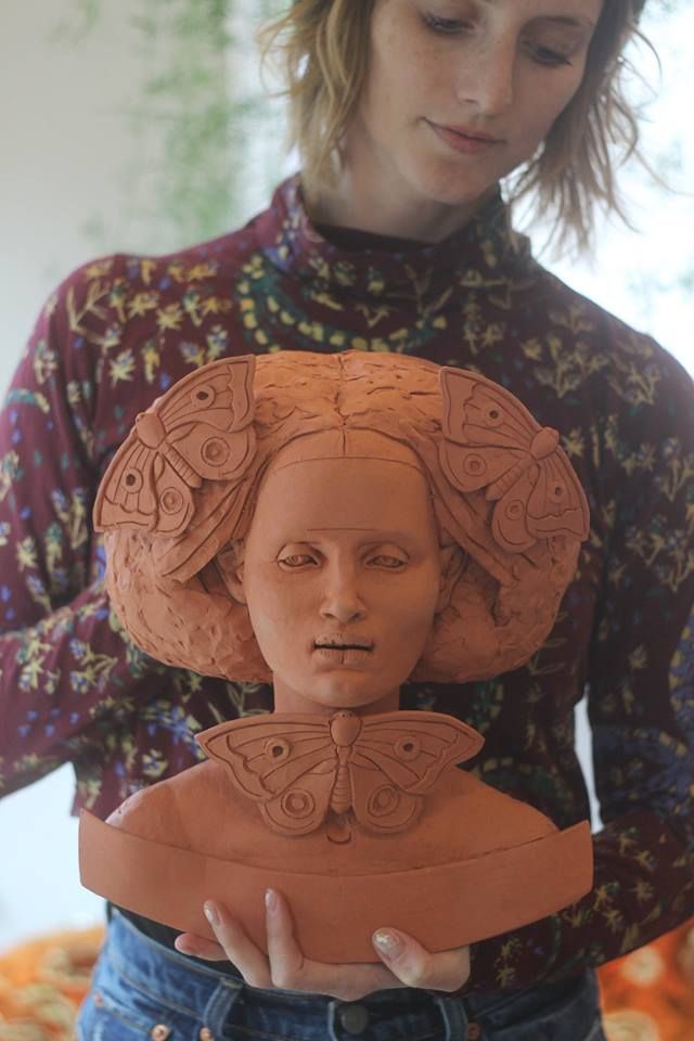 a woman is holding a clay sculpture in her hands