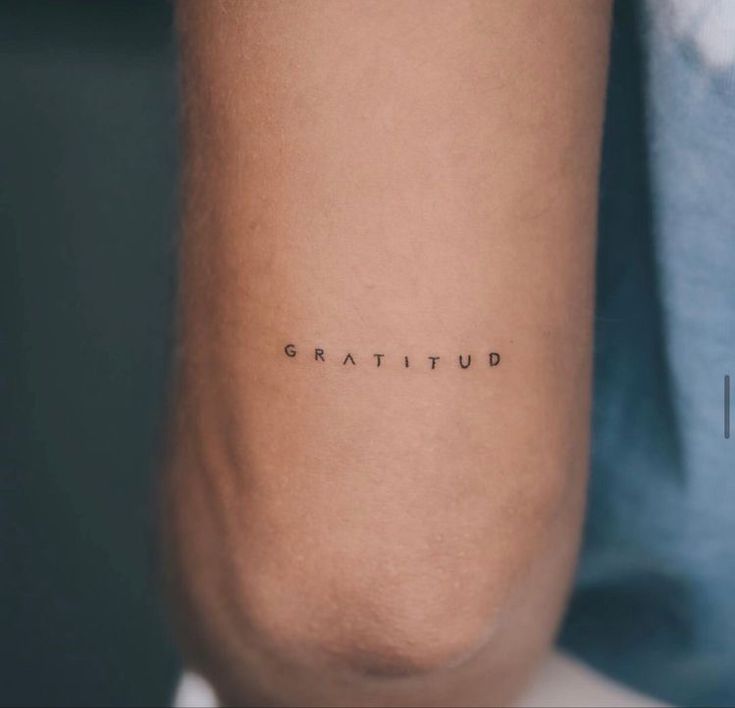 the word gratitud written in cursive font on someone's arm