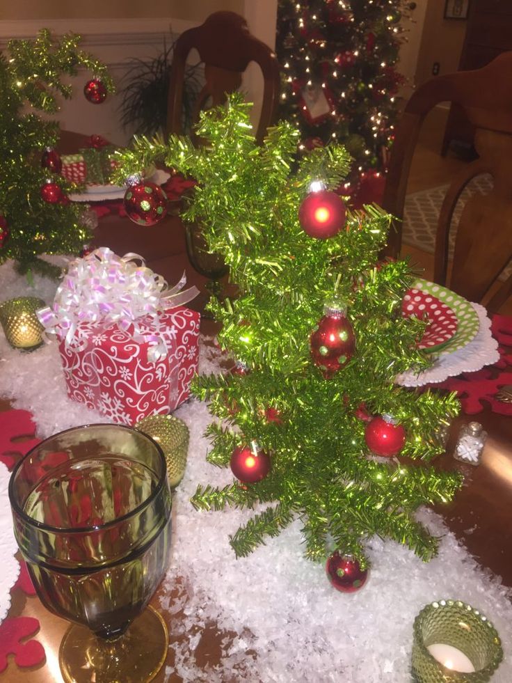 a christmas table setting with presents on the table and other holiday decorations around it, including a small tree