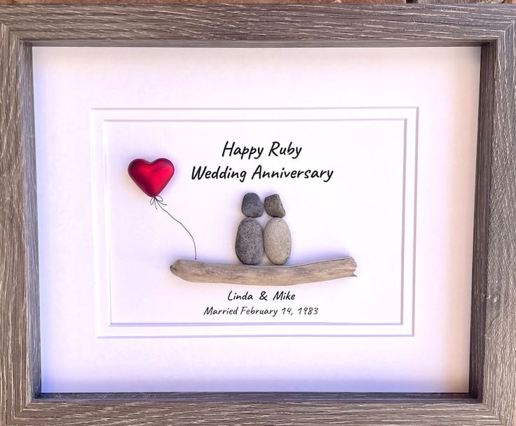 two rocks sitting on top of a wooden frame with a red balloon in the middle