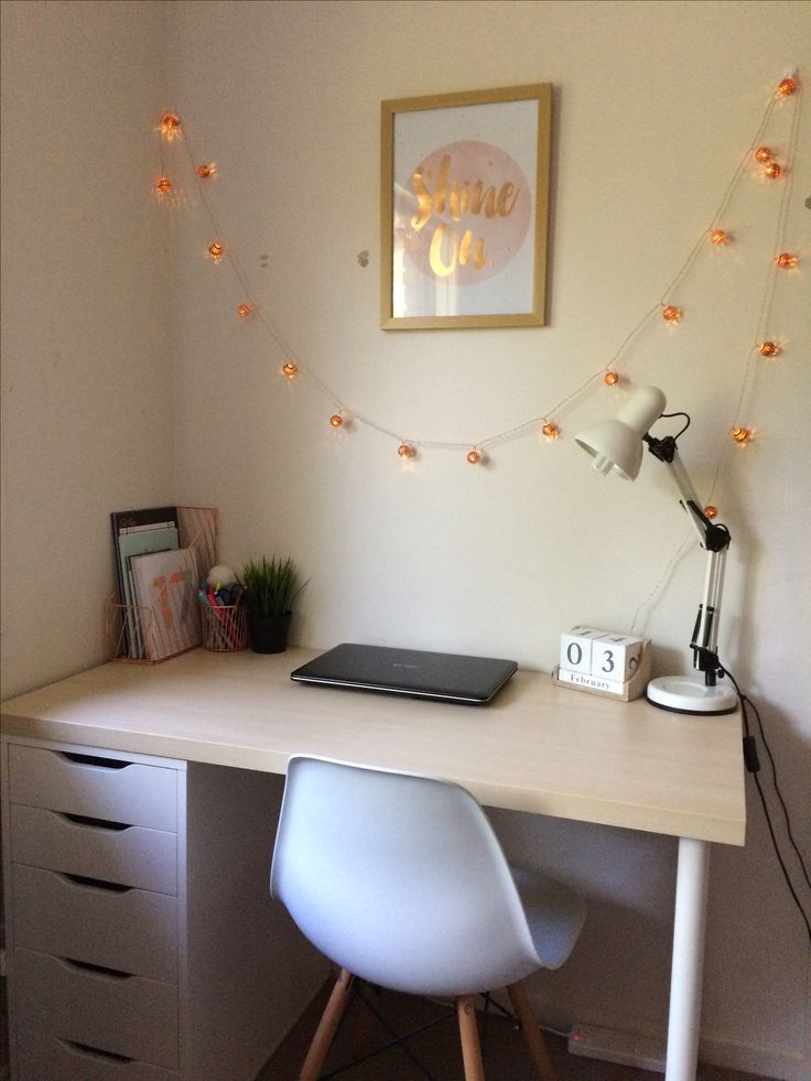 a white desk with a laptop computer on top of it next to a lamp and pictures