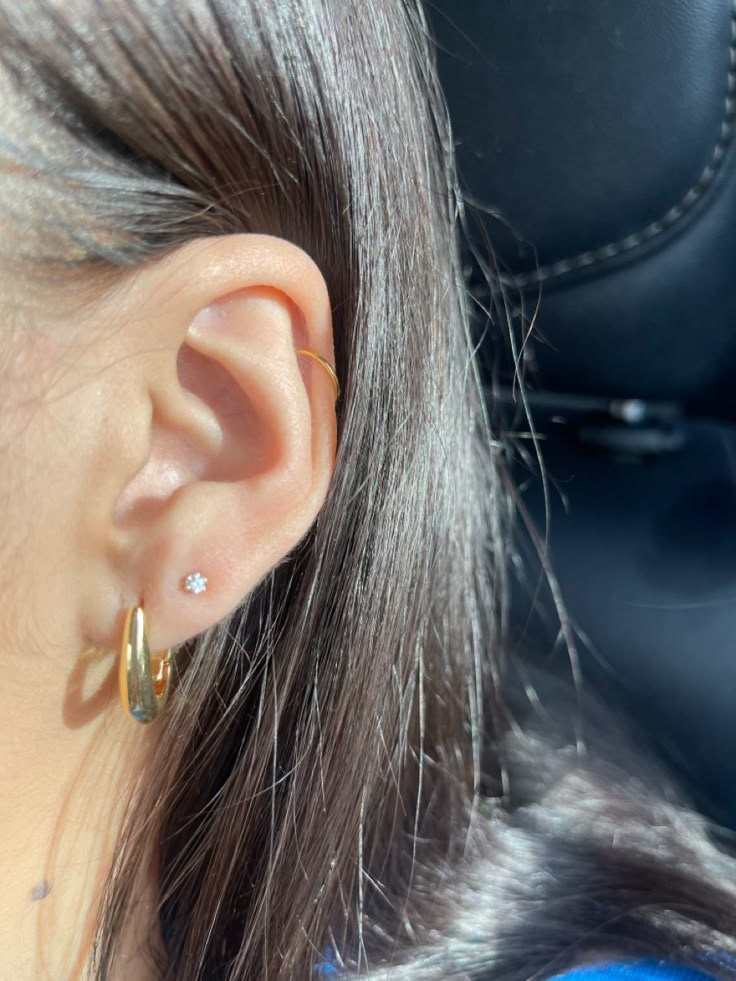 a close up of a person's ear with two small gold hoops on it