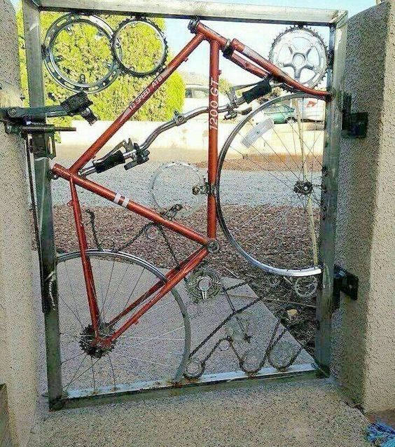 an orange bicycle locked to a metal gate