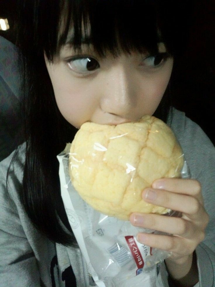 a young woman eating a pastry wrapped in plastic