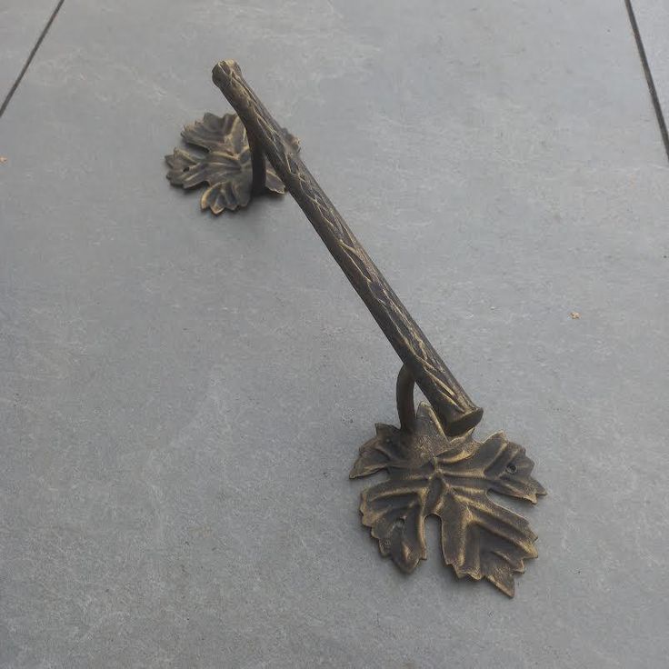 an old style metal door handle with leaves on the top and bottom, sitting on concrete